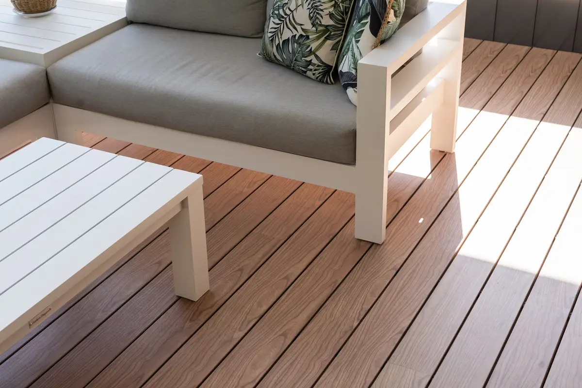 Close view of timber-look aluminium deck boards and their shadow-line gaps beneath an outdoor lounge