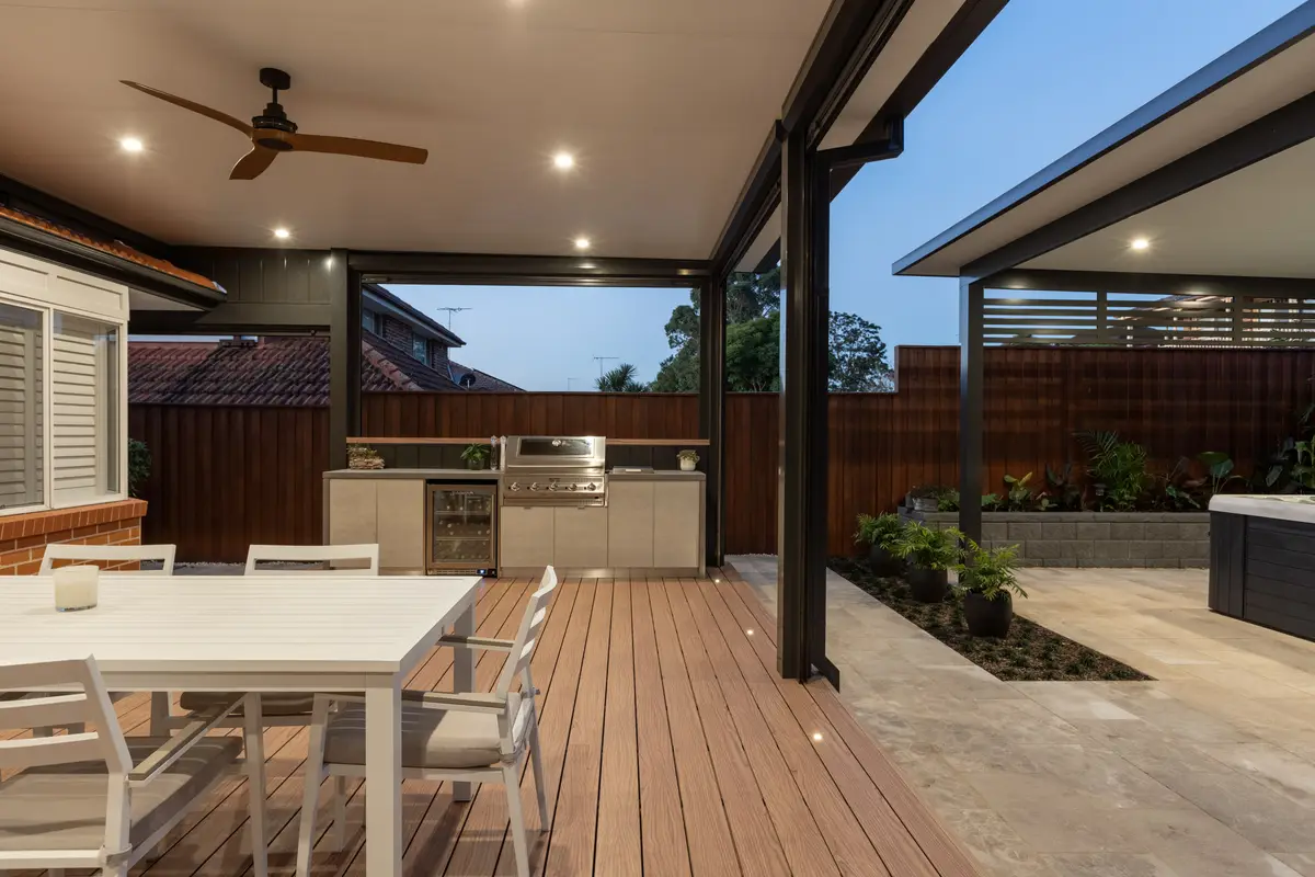 Deck and outdoor kitchen lit at dusk, in-floor lights set along the boards