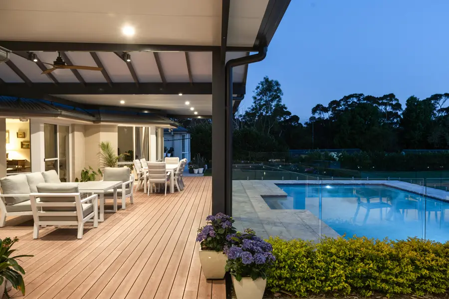 Lounge and dining on the deck at dusk, the pool lit alongside