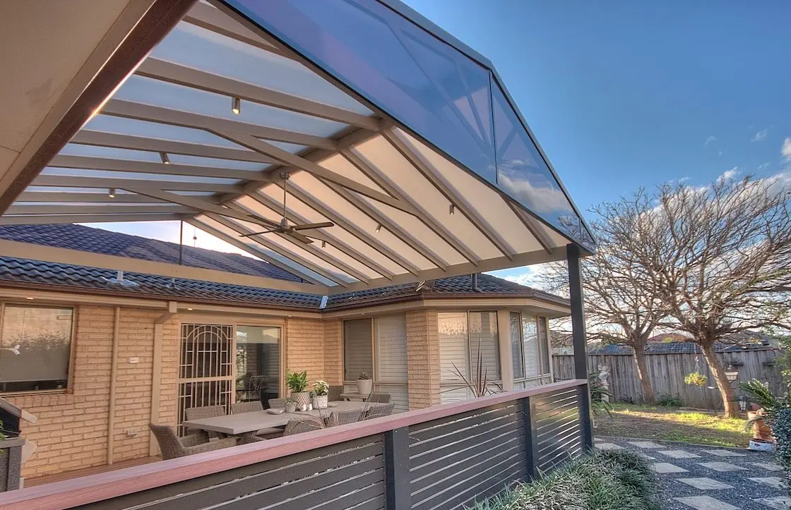 Gabled polycarbonate roof on exposed beams, filtering daylight through translucent panels with no visible fixings