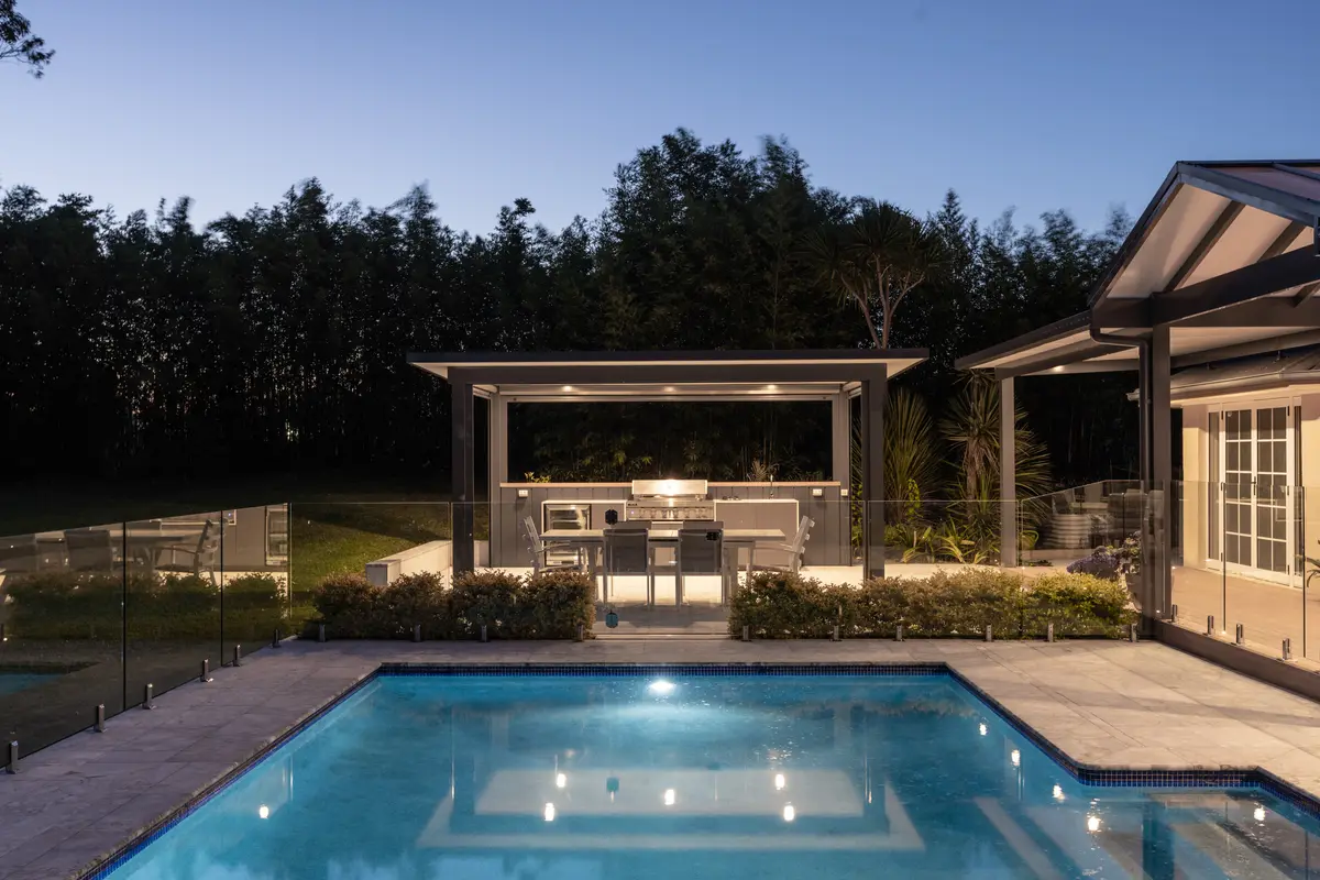The cabana and lit pool at dusk, framed by the bamboo screen, Annangrove