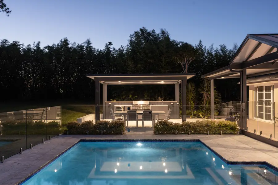 The cabana and lit pool at dusk, framed by the bamboo screen