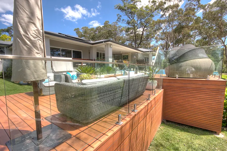 Frameless glass balustrade fixed along the deck edge above the garden