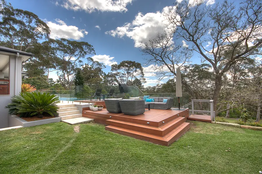 The raised aluminium deck platform sitting into the lawn, with glass and wire balustrade