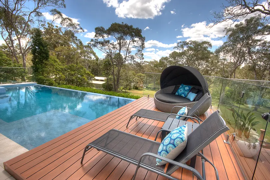 Loungers and a daybed on the deck beside the infinity edge, bush beyond
