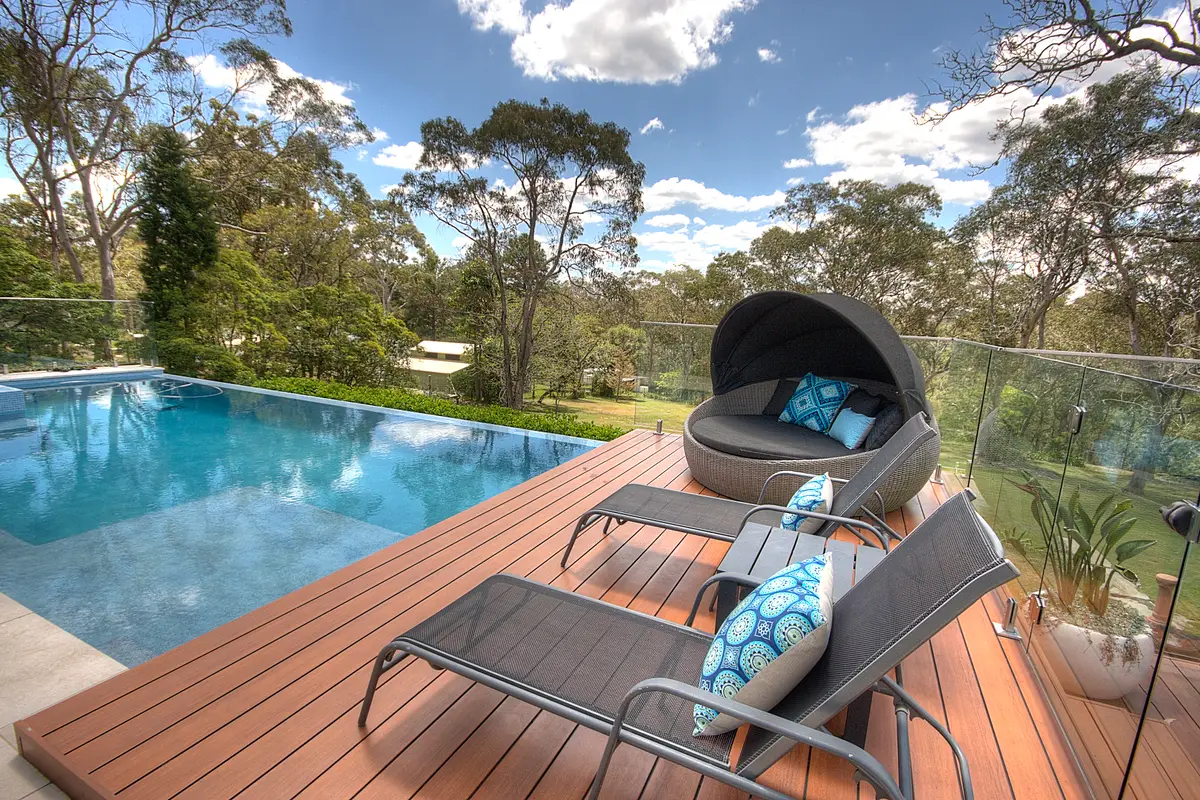 Aluminium deck boards running to the infinity edge, loungers and a canopied daybed on the deck