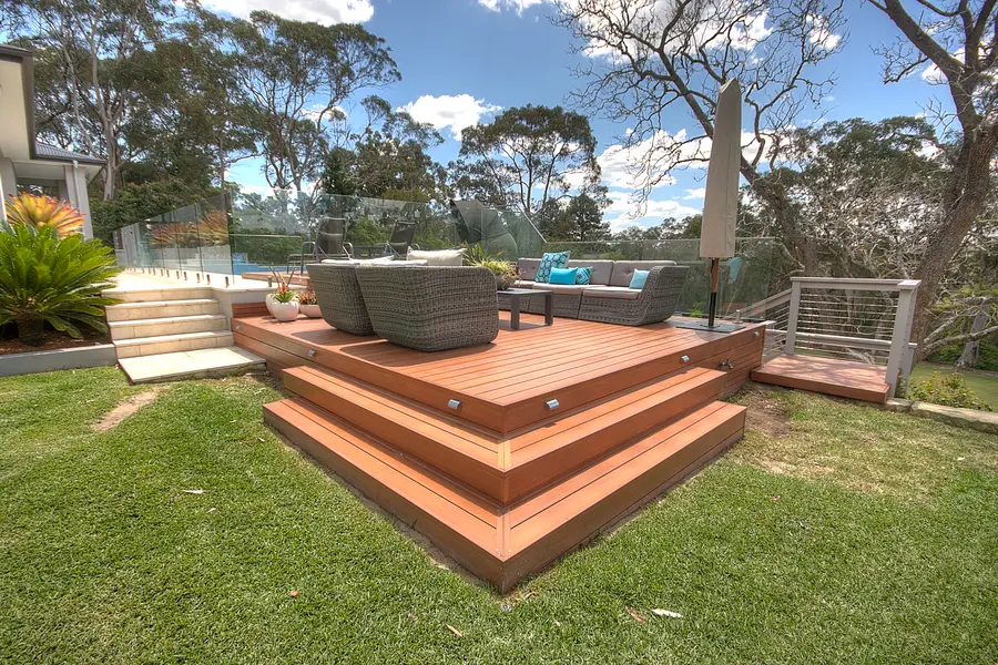 Aluminium decking stepping down to the lawn in broad mitred treads, pool behind