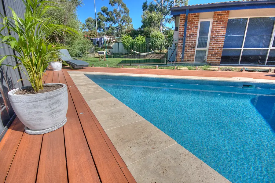 Aluminium decking wrapping the pool, travertine coping between board and water