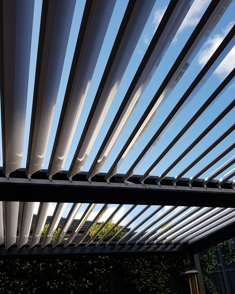 Looking up at a louvred opening roof with the blades part open to the sky