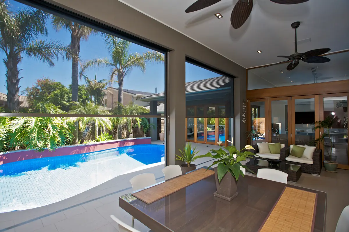 Blinds down the side of a dining area, palms and the pool visible through the fabric