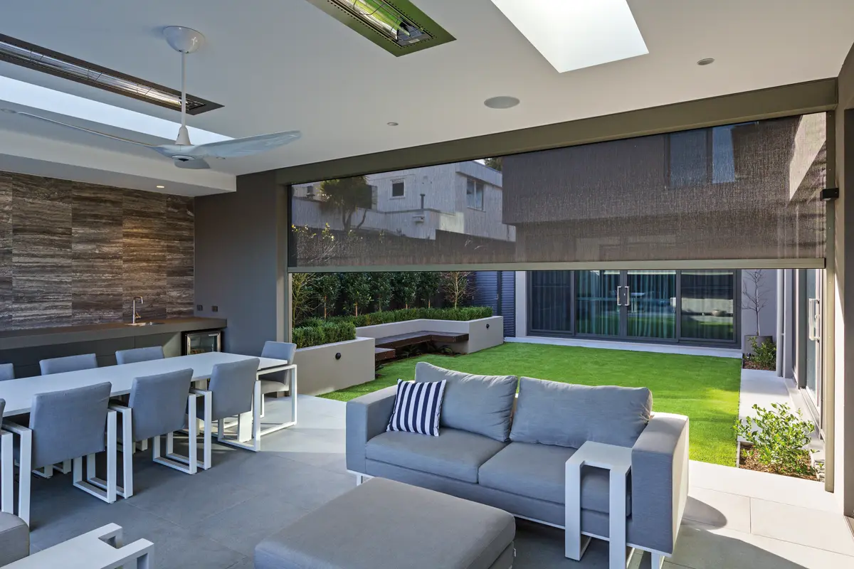 Mesh blind lowered halfway across an alfresco opening, the lawn and garden visible straight through it