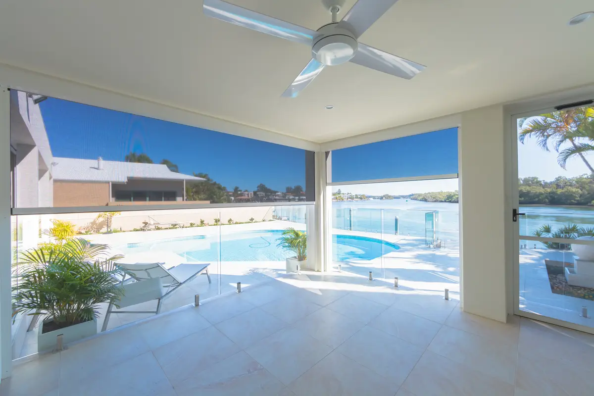 Two blinds lowered across a waterfront alfresco, the pool and river showing through the mesh