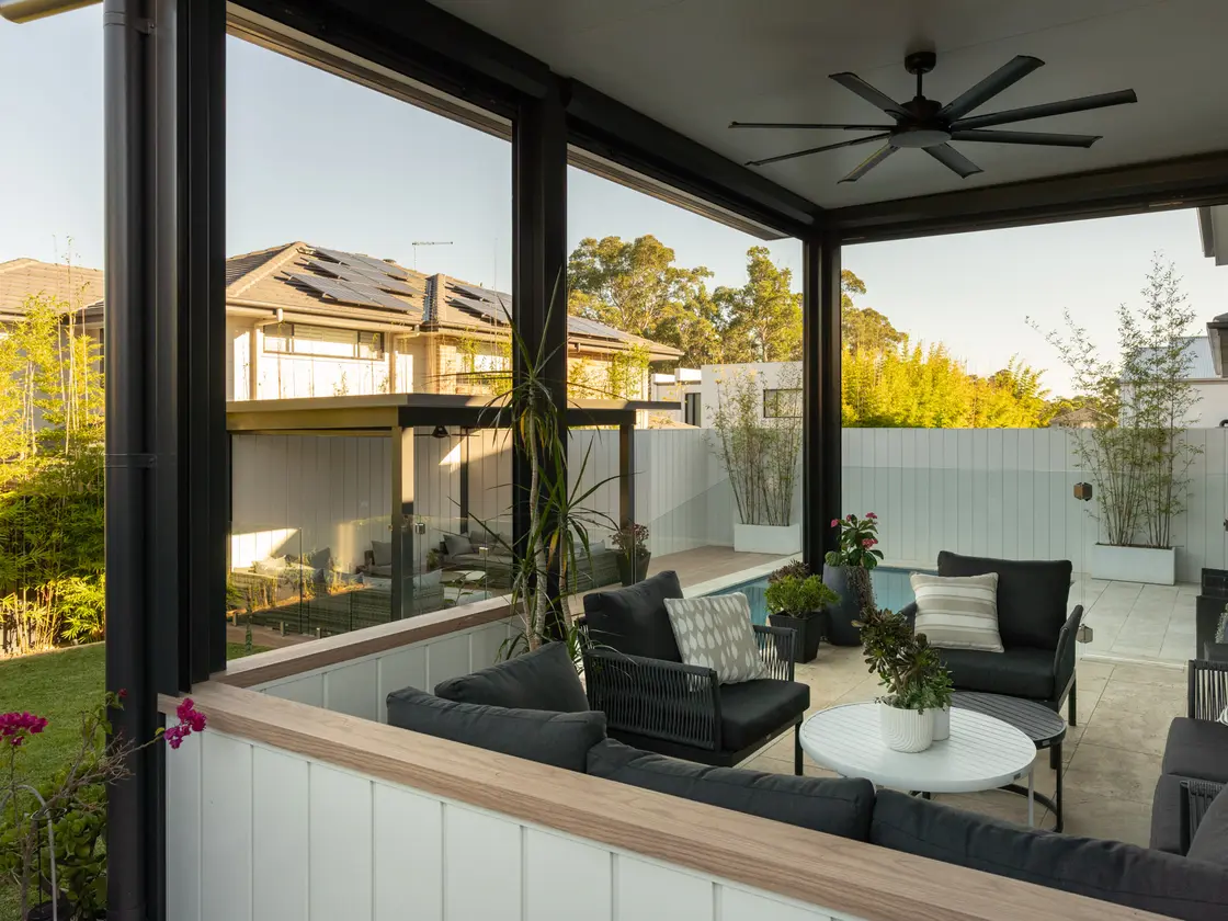 Waist-height white clad wall enclosing an alfresco, open above to the garden, ceiling fan overhead