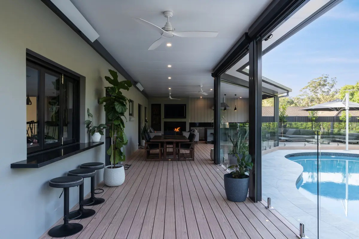 Deck running the length of the alfresco past a window servery, pool alongside