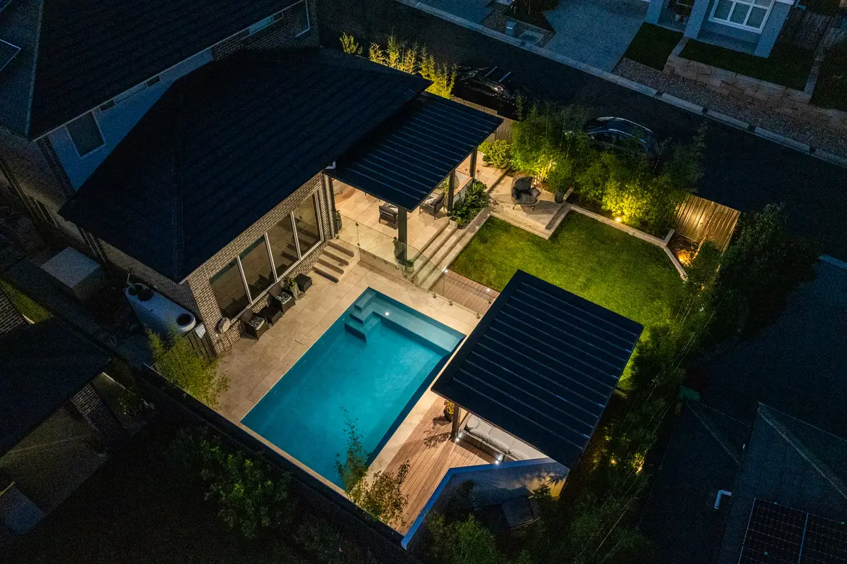 Elevated view at dusk, the lit alfresco and pavilion framing the pool, North Kellyville
