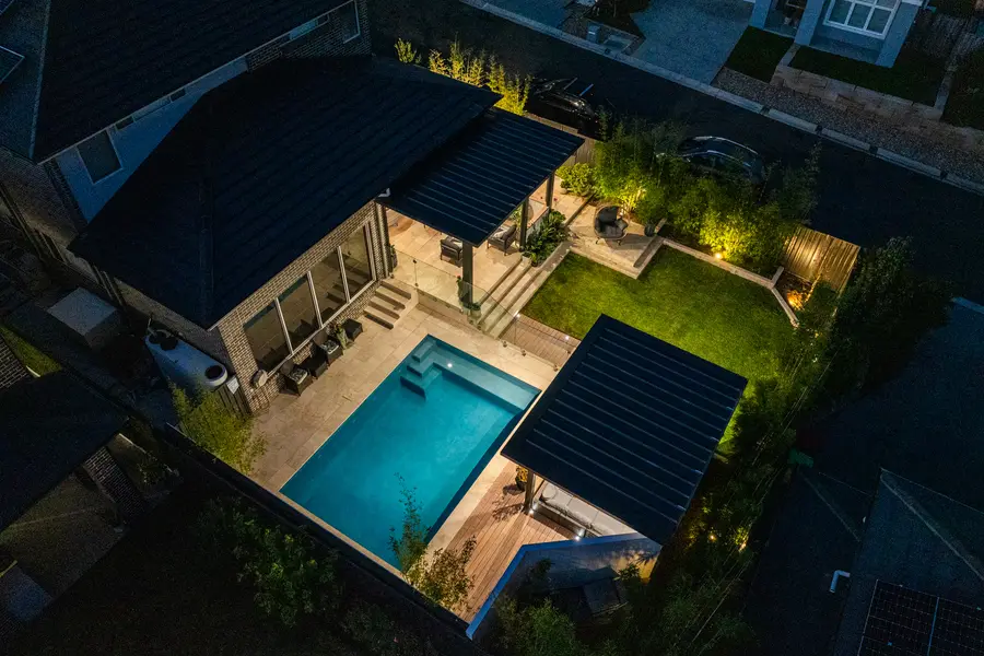 Elevated view at dusk, the lit alfresco and pavilion framing the pool