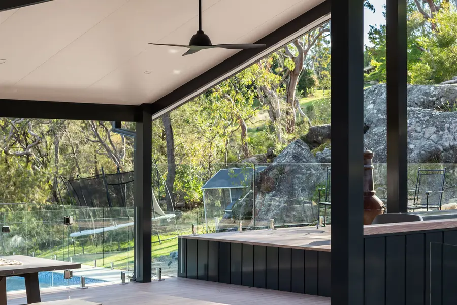 The raised deck edge finished in dark powder-coated cladding, with the chiminea alongside