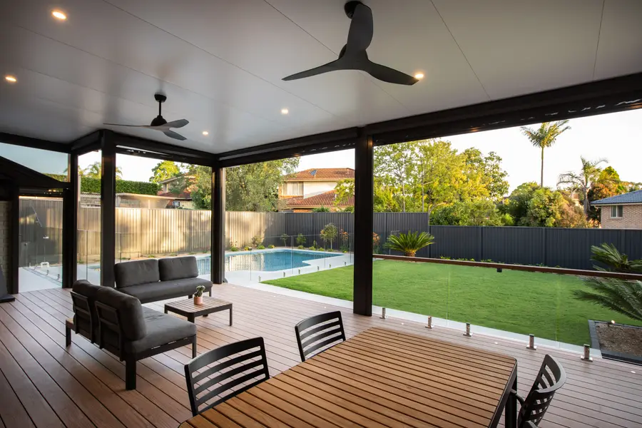Late afternoon sun across the deck, pool and lawn beyond the balustrade