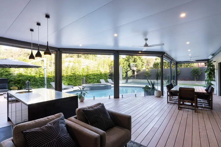 Lounge and dining laid out along the deck, open to the pool and court