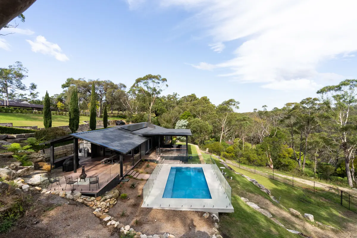 The deck and pool set into the slope, seen from above with bushland all around