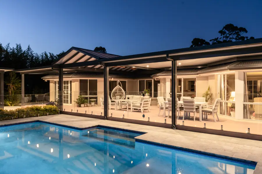 The full rear elevation lit at dusk, seen across the pool