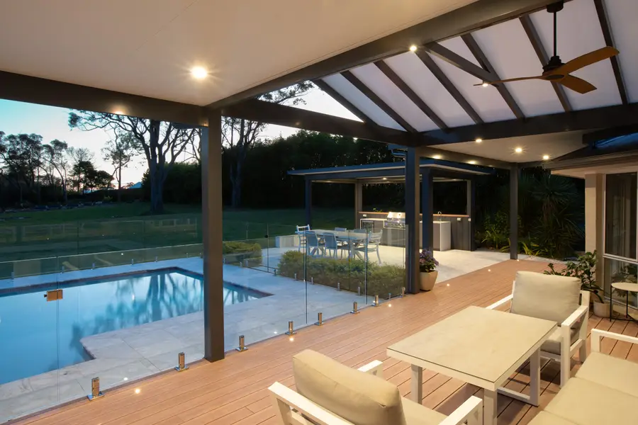Downlights and in-deck lighting under the gable at dusk, looking to the cabana