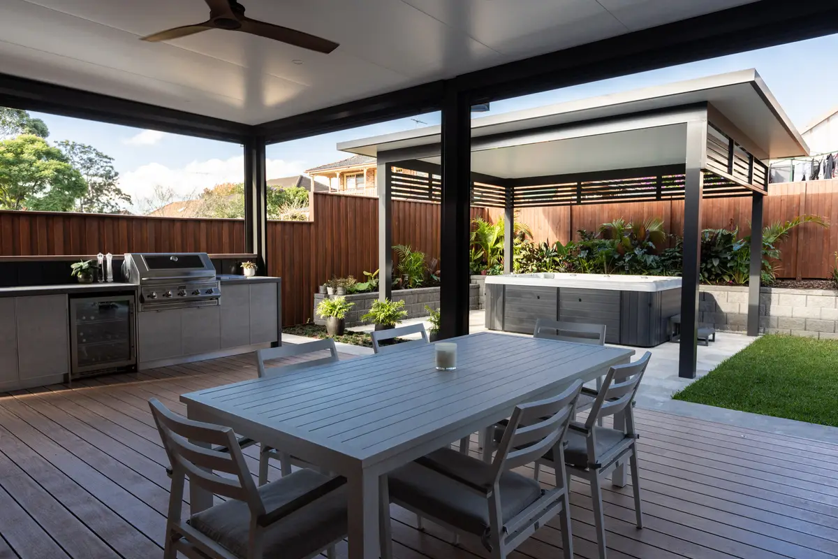 Aluminium deck running under a pergola to an outdoor kitchen and dining setting