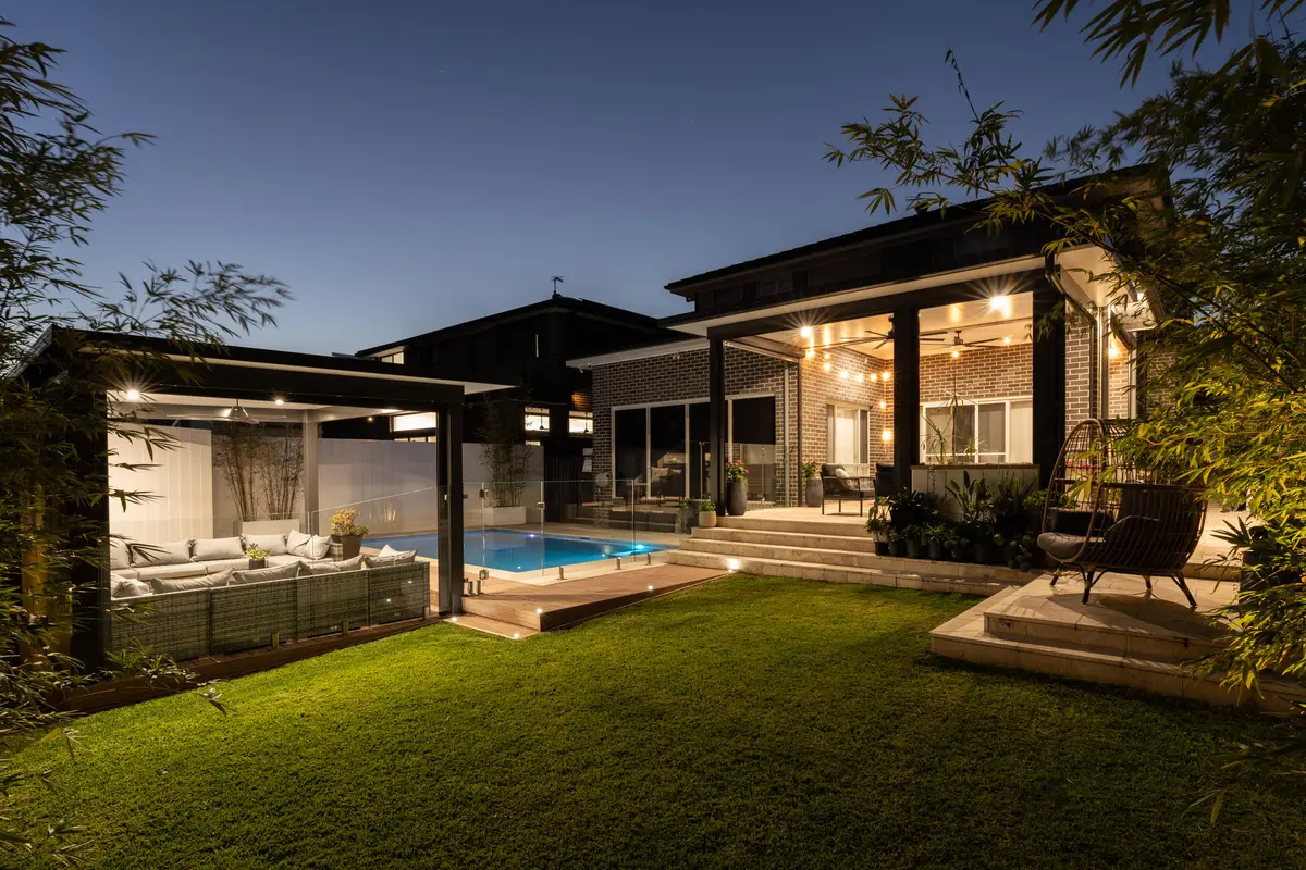 The pavilion, pool and festoon-lit alfresco at dusk, North Kellyville