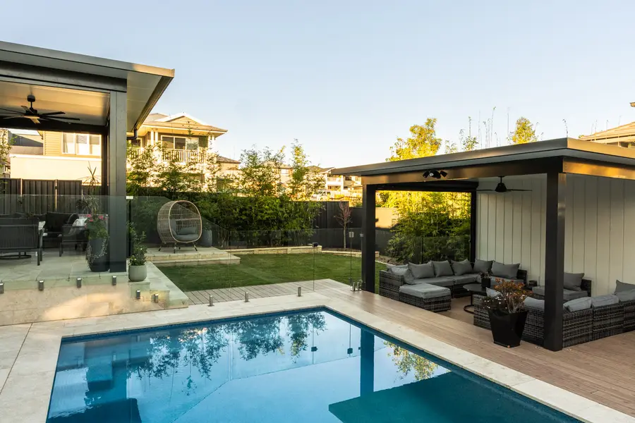 The pool between the two structures, lawn and hanging chair beyond