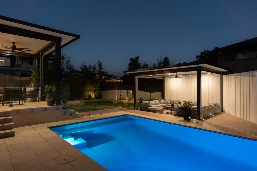 The pool lit blue after dark, both structures glowing either side