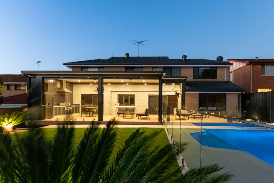 The whole rear elevation lit at dusk, from the far side of the pool