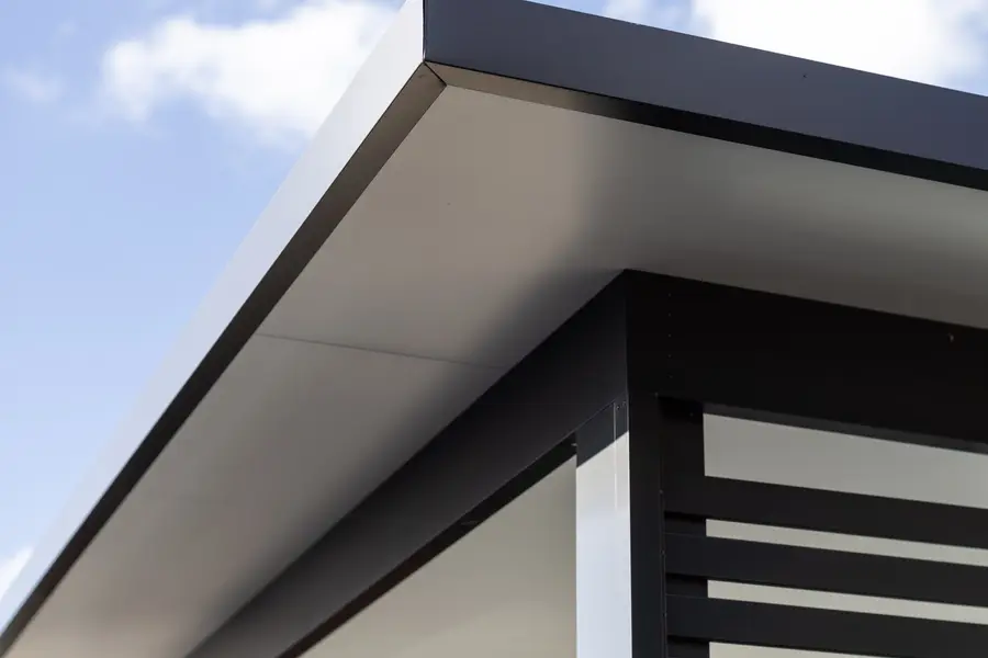 Corner detail of the cabana roof and aluminium slat screen against the sky