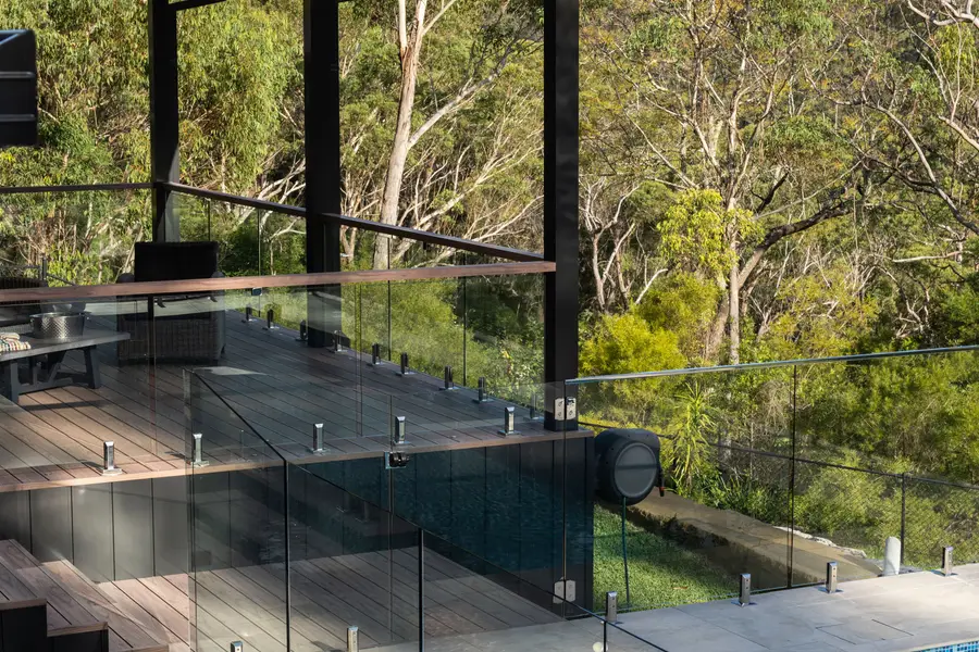 Deck steps down to the pool beside a frameless glass balustrade with a timber-look top rail