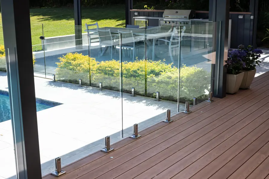 Frameless glass pool fencing on polished spigots, meeting the aluminium deck