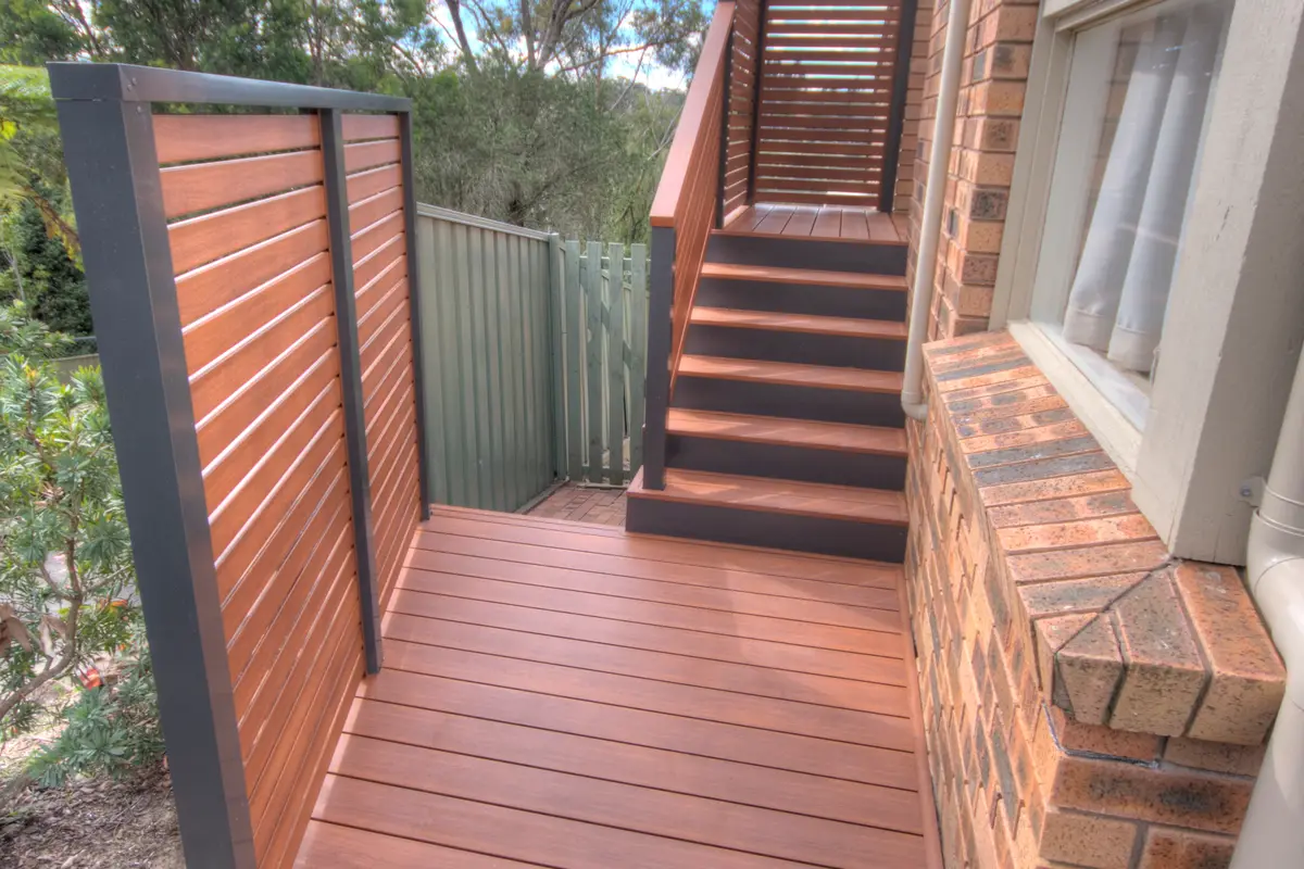 Slat screening enclosing a deck landing beside the house, with stairs and a matching slat balustrade beyond