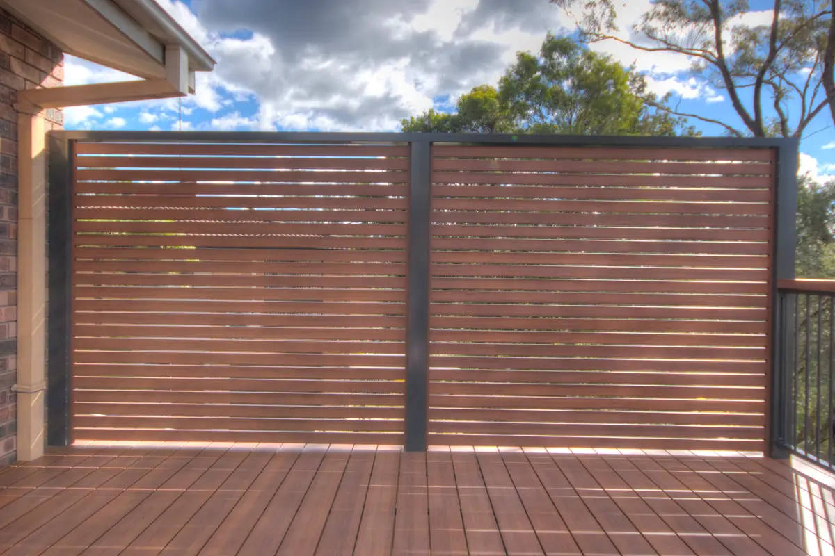 Two slat screen panels closing off the end of a deck, sunlight coming through the gaps between the timber-look slats